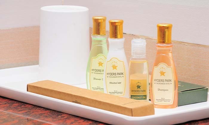 Hyderspark-branded shampoo, shower gel, moisturiser and coconut oil on a tray with a dental kit