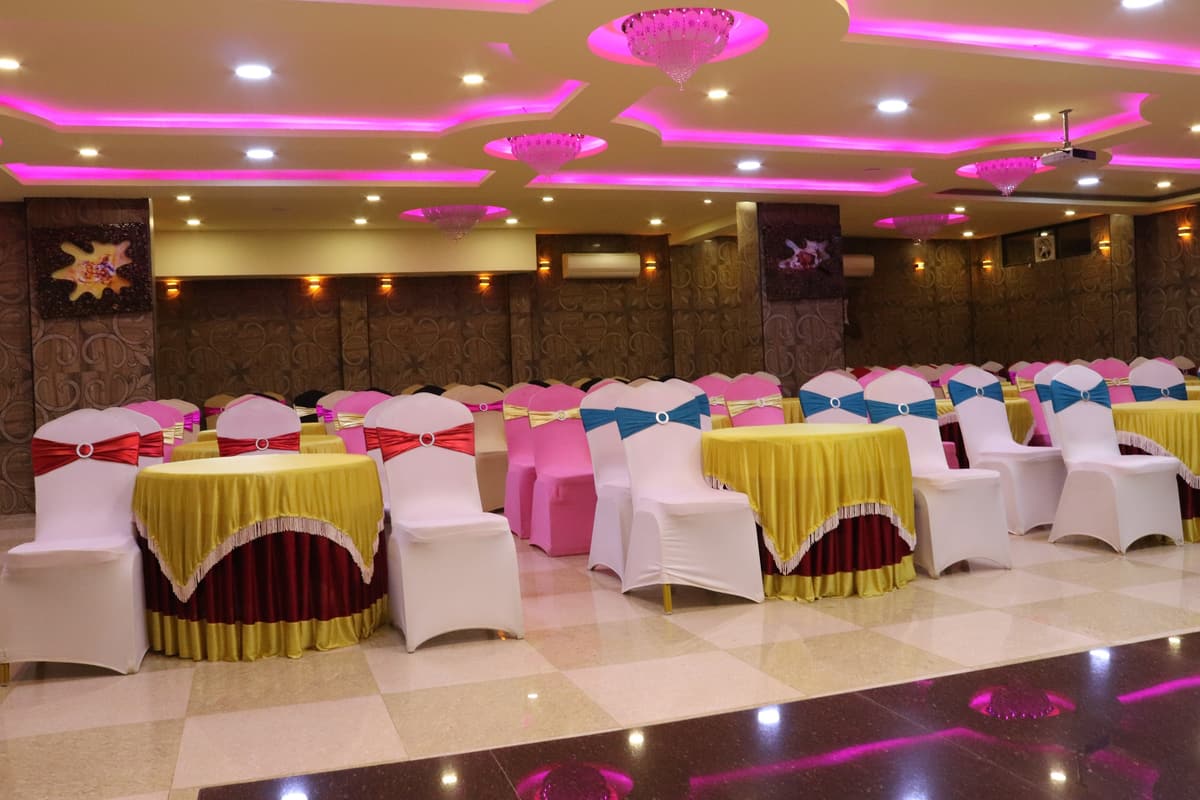 Thalam Party Hall with rows of dressed tables and chairs beneath a lit pink-and-white ceiling
