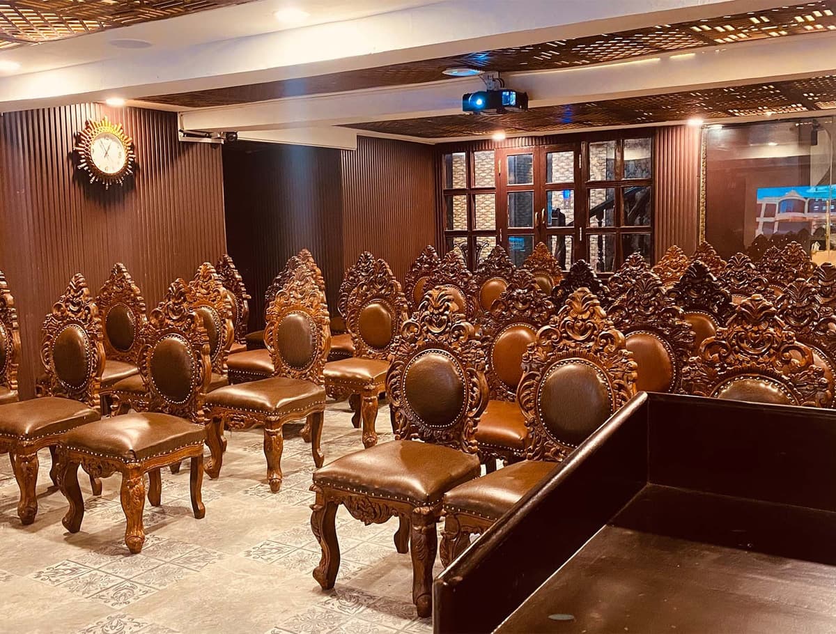 The Jasmin Meeting Hall with rows of carved wooden chairs and a ceiling projector