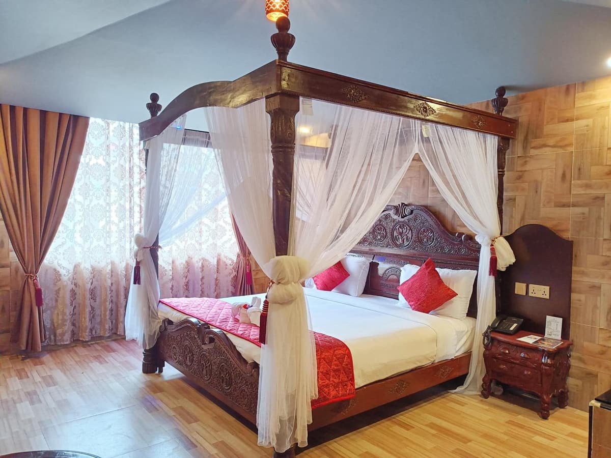 Park Honey four-poster bed with white canopy curtains and red cushions