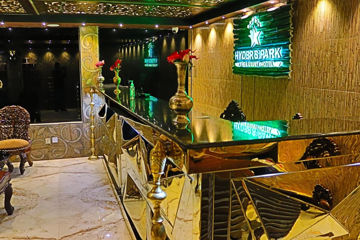 The golden reception desk beneath the hotel's lit green sign
