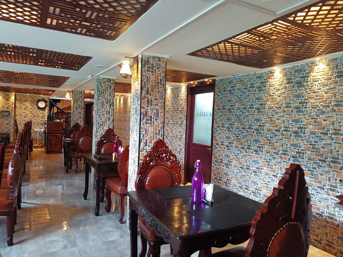 Carved chairs and dark tables beside a stone-clad wall