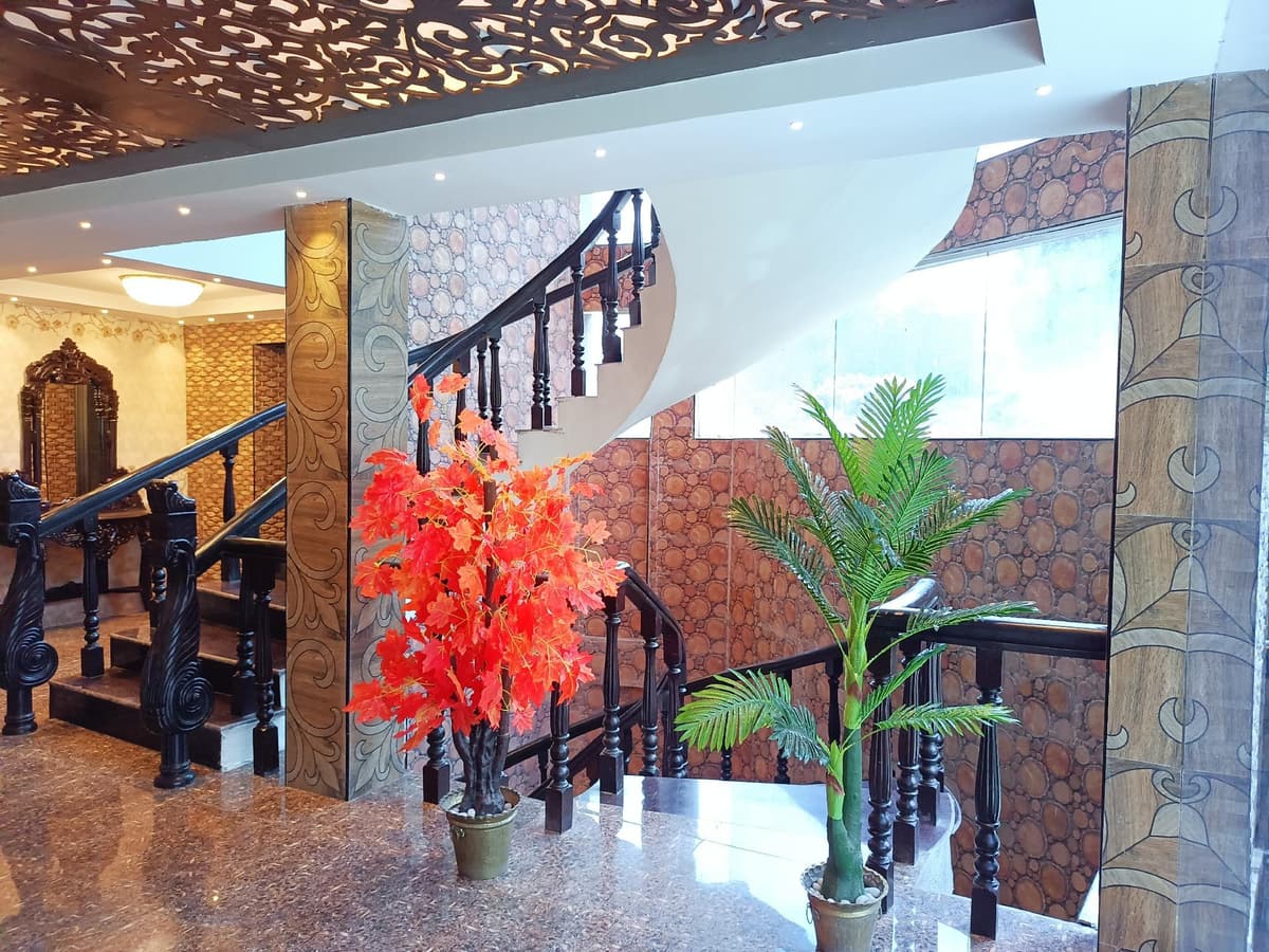 The lobby staircase with a carved banister and a red-flowered tree