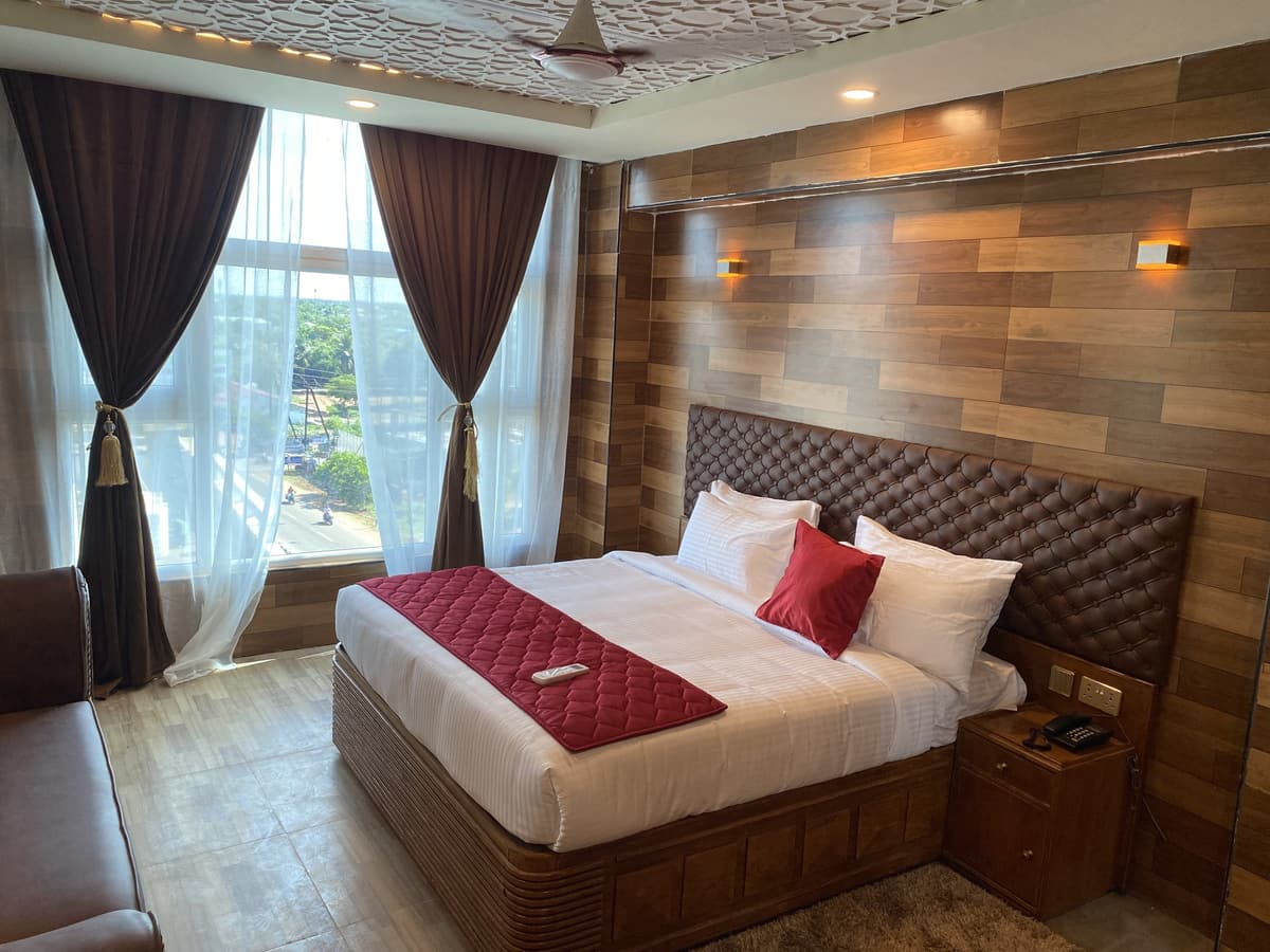 Park Palace bedroom with warm timber-panelled walls, a tufted headboard and tall curtained windows